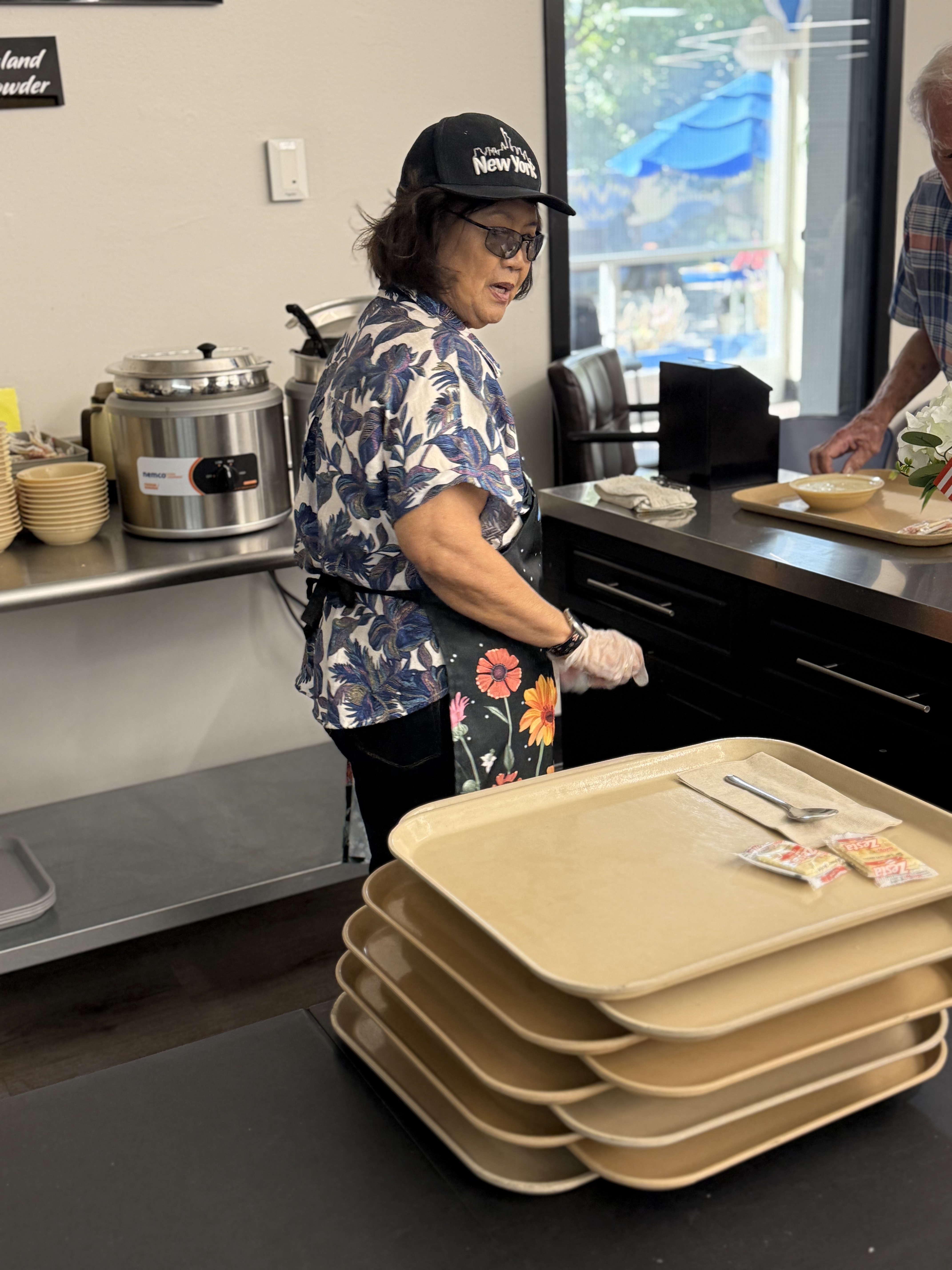 Image of a worker handing out food trays at a meal site